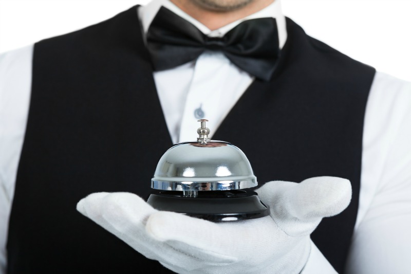 Midsection of young butler holding service bell over white background ** Note: Shallow depth of field